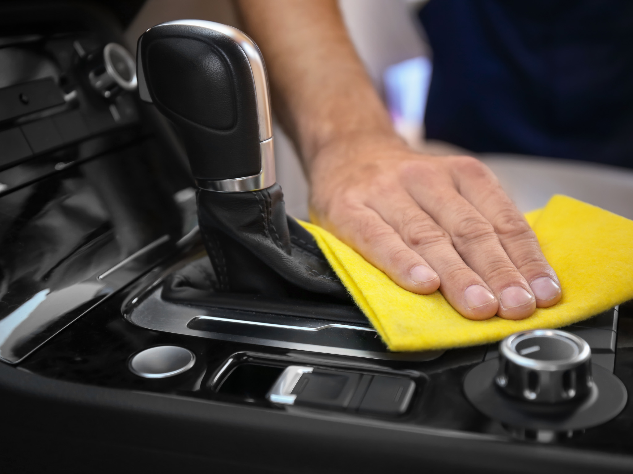 Man cleaning car gear lever with rag, closeup