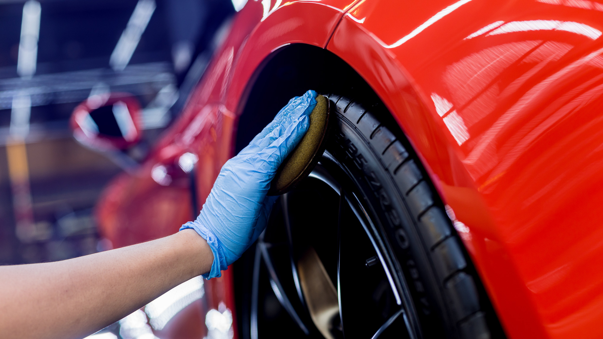 Car service worker polishing car wheels with microfiber cloth.